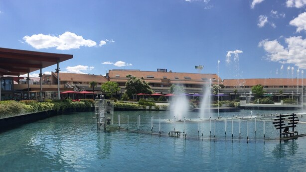 A hotel with a large outdoor pool featuring multiple fountains, surrounded by greenery and a clear blue sky. - Hotel AR Parquesur (Leganes)