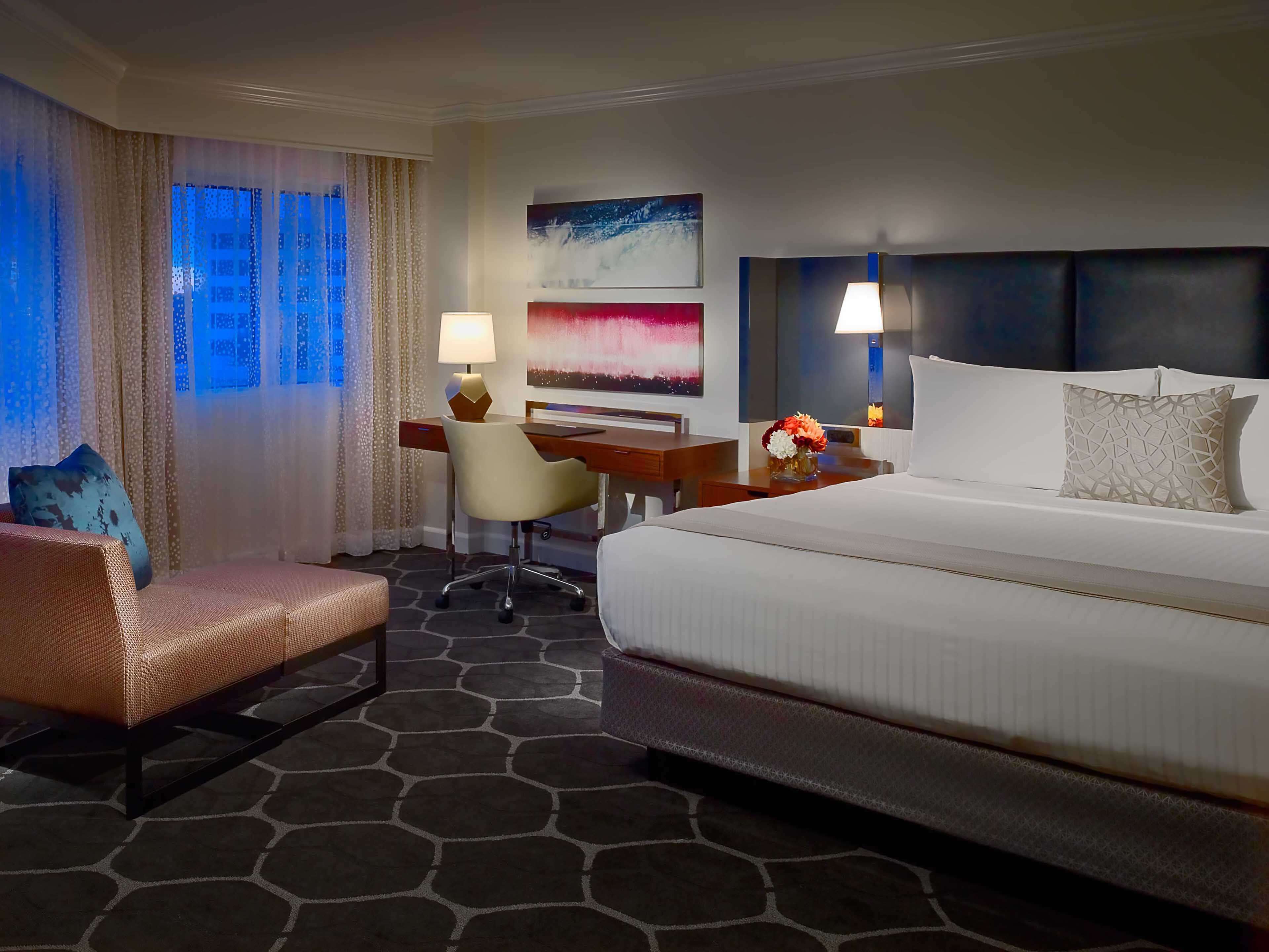 A hotel room with a bed, a desk, a chair, and a couch.
