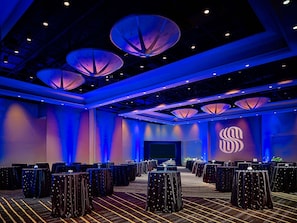 A conference room with tables, a stage, and a large logo on the wall. - The Royal Sonesta Houston Galleria (Houston)