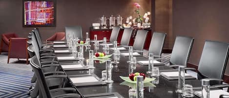 Une salle de conférence avec une longue table, des chaises et un lustre.