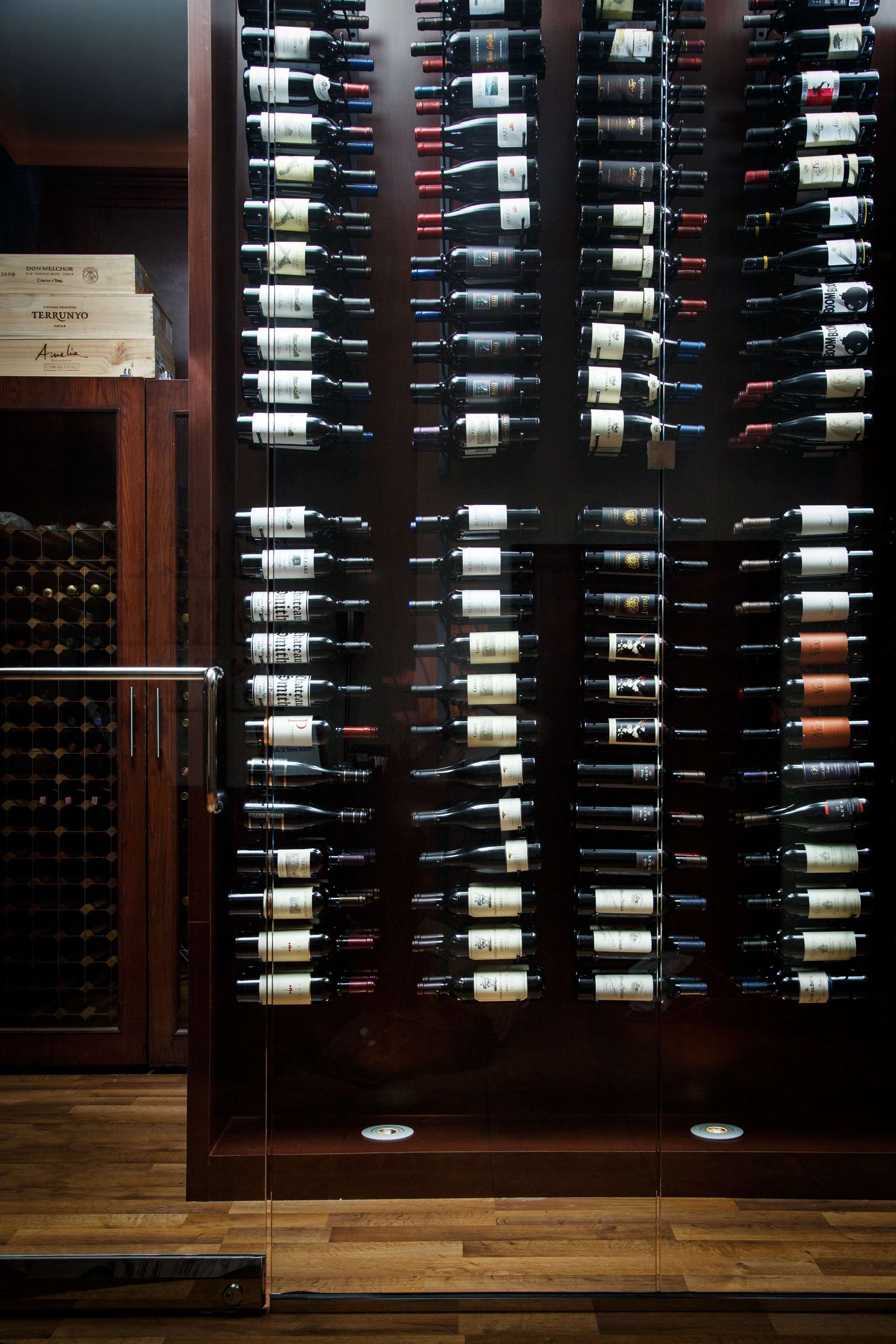 A wine rack with multiple bottles, a wooden cabinet, and a wine cooler.
