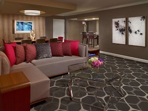 A modern living room with a sectional sofa, a glass coffee table, and a dining area with chairs and a table.
