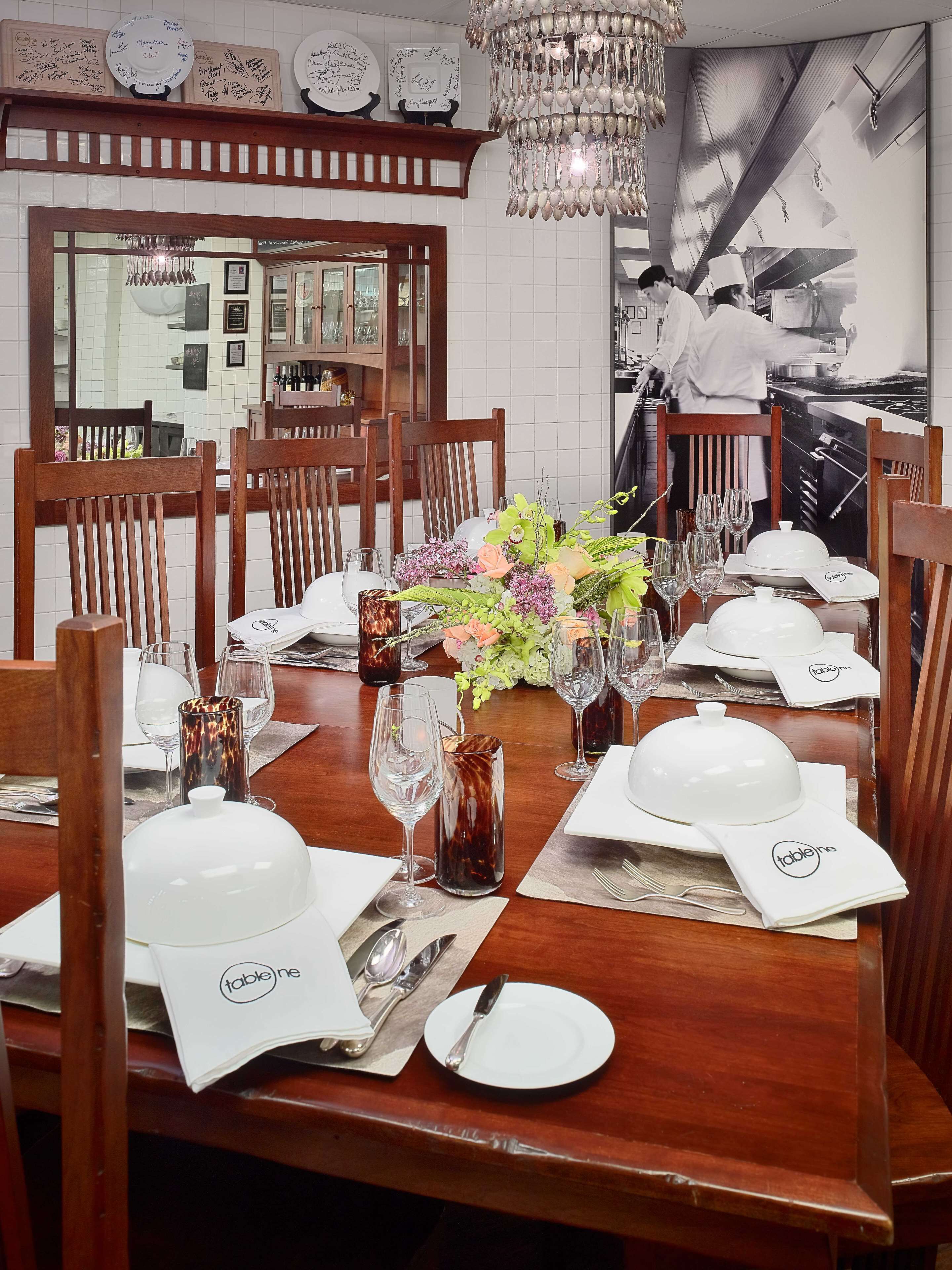Uma sala de jantar com mesas e cadeiras de madeira, e um candelabro.