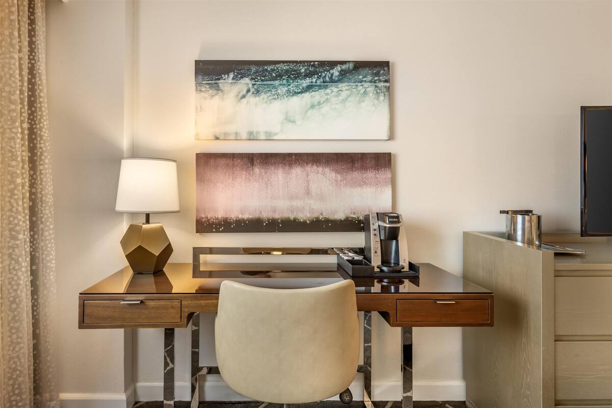 Une chambre d’hôtel équipée d’un bureau, d’une lampe, d’une machine à café et d’un téléviseur.