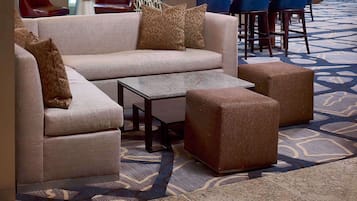A modern lounge area with a sofa, ottoman, and bar seating.