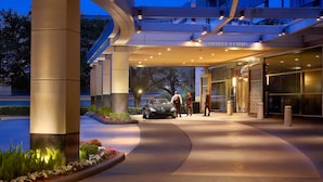 A hotel entrance with a modern design, a covered walkway, and a car parked outside.
