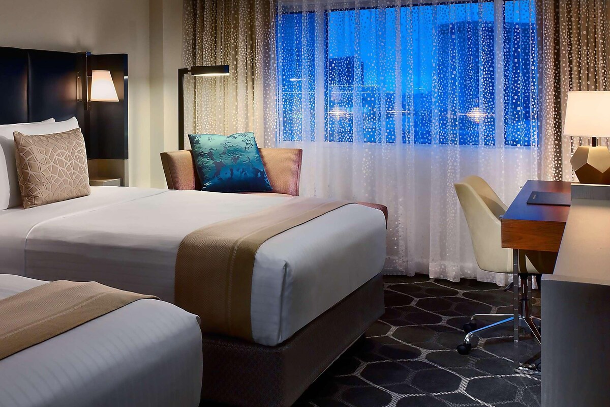 Une chambre d’hôtel avec deux lits, un bureau et une chaise.