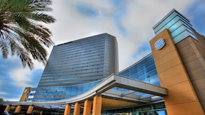 A modern hotel with a curved entrance, a prominent logo, and a glass facade.