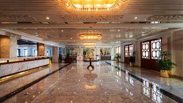 A spacious lobby with a marble floor, a grand chandelier, and a reception desk.