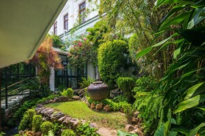 A lush garden with a large pot, rocks, and various plants.