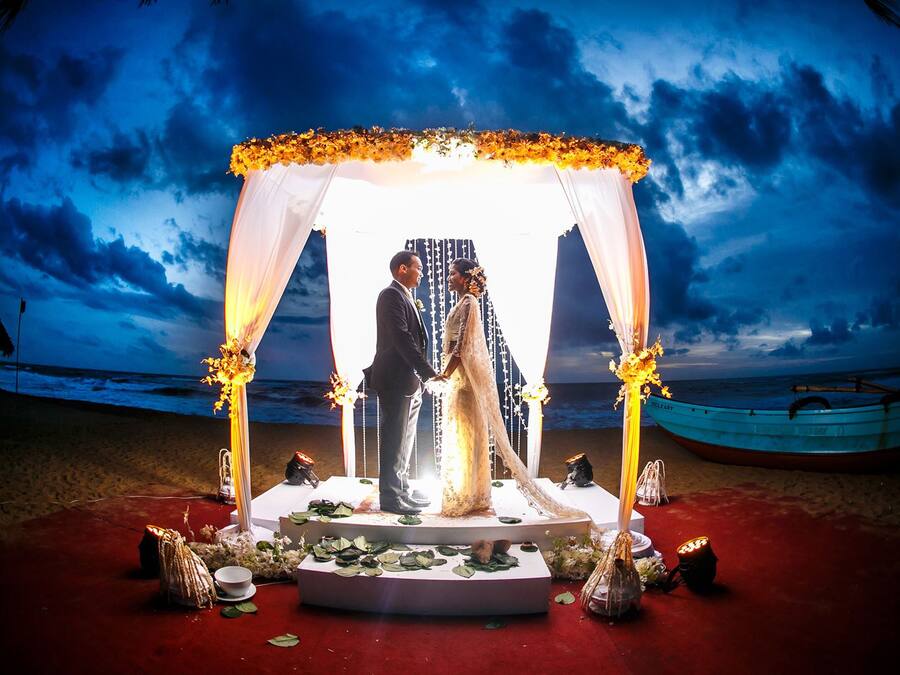 A wedding ceremony setup with a canopy, floral decorations, and a boat in the background.