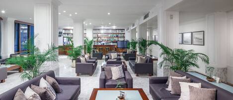 Un hall d’entrée spacieux avec plusieurs coins salon, un bar et un téléviseur.