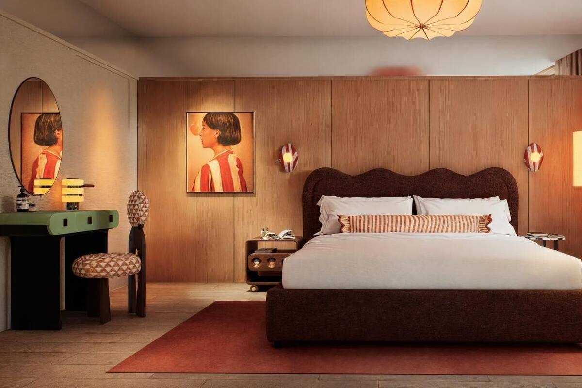 A bedroom with a large bed, a wooden headboard, a nightstand, a bedside table, a mirror, and a window with curtains.