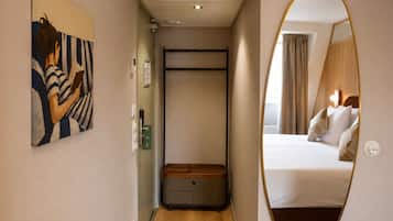 Habitación de hotel con cama, mesita de noche, espejo y un cuadro en la pared.