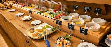 A buffet with various food items and labels in a wooden setting.