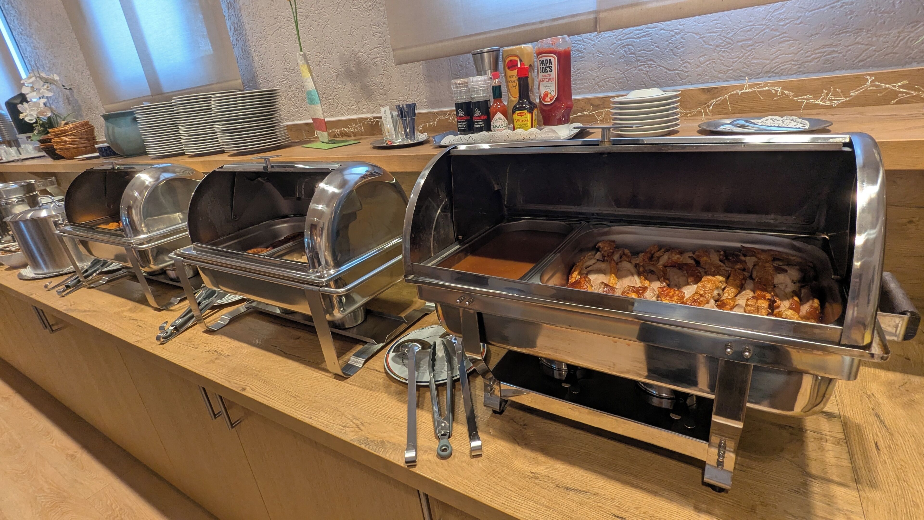 A buffet setup with multiple self-service chafing dishes, condiments, and serving utensils.