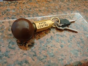 Un llavero con una llave de hotel y un objeto marrón que dice 'HOTEL CENTRO' sobre una encimera de granito.