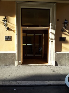 Entrada de hotel con puerta de vidrio, un letrero que dice 'Hotel Centro' y dos faroles en la pared.
