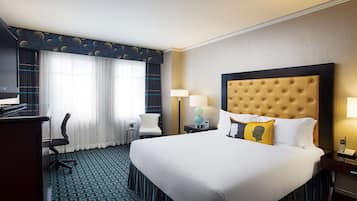 Una habitación de hotel con una cama grande, un escritorio, una silla, una lámpara y una mesita de noche.