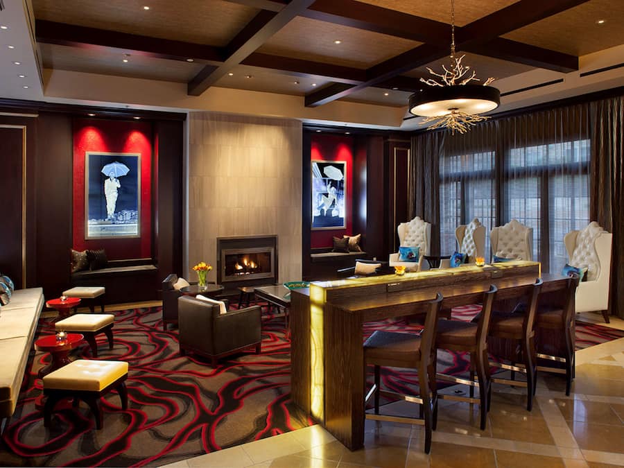 A modern lobby with a fireplace, seating area, and a bar with high stools.