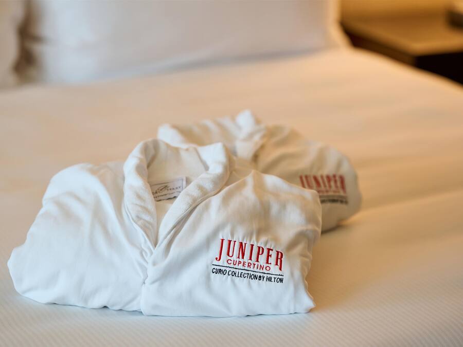 Dos bolsas blancas con el texto 'JUNIPER' y 'CURIO COLLECTION BY HILTON'.