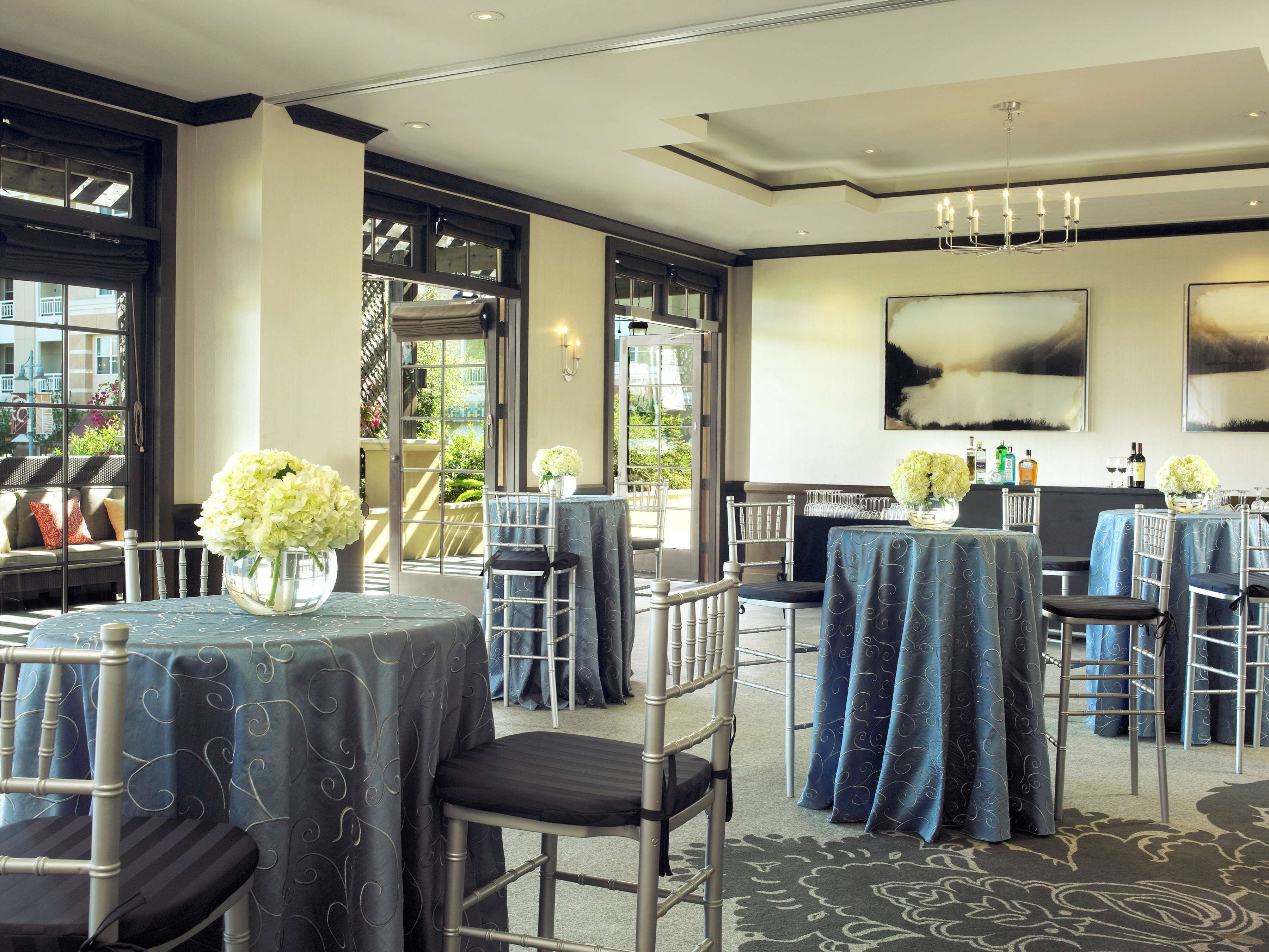 A hotel dining area with tables set for guests, chairs, and a view of the outdoors.