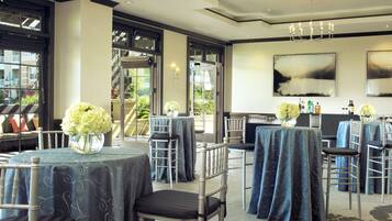 A hotel dining area with tables set for guests, chairs, and a view of the outdoors.