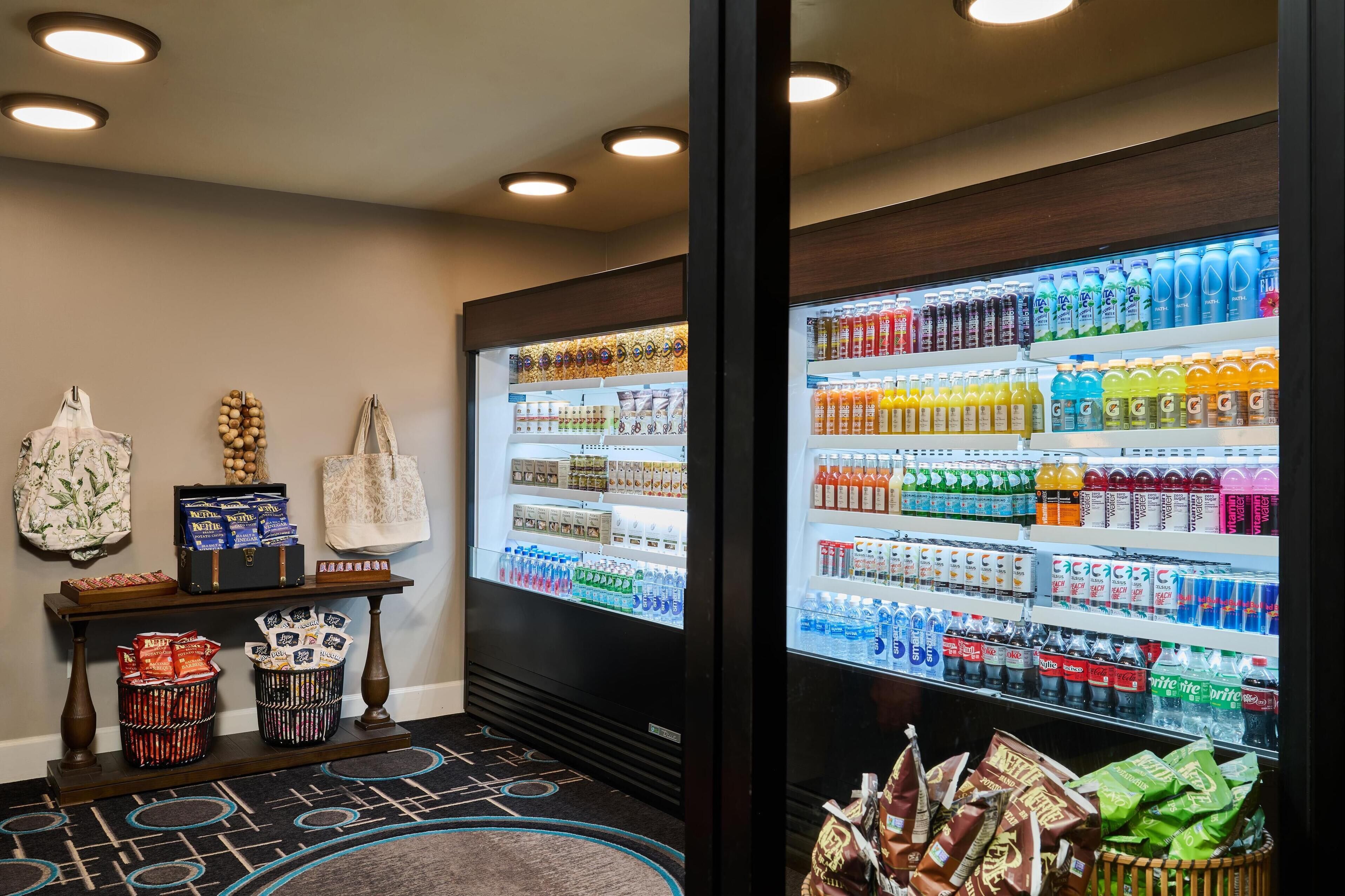 Un área de venta automática con diversas bebidas y aperitivos, incluyendo agua embotellada, zumos y tentempiés.
