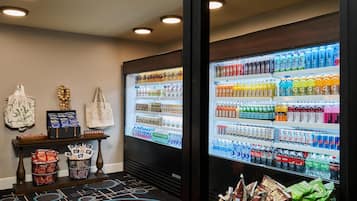 Un área de venta automática con diversas bebidas y aperitivos, incluyendo agua embotellada, zumos y tentempiés.