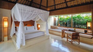 Um quarto espaçoso com cama de dossel, área de estar com vista para vegetação exuberante e uma janela grande.