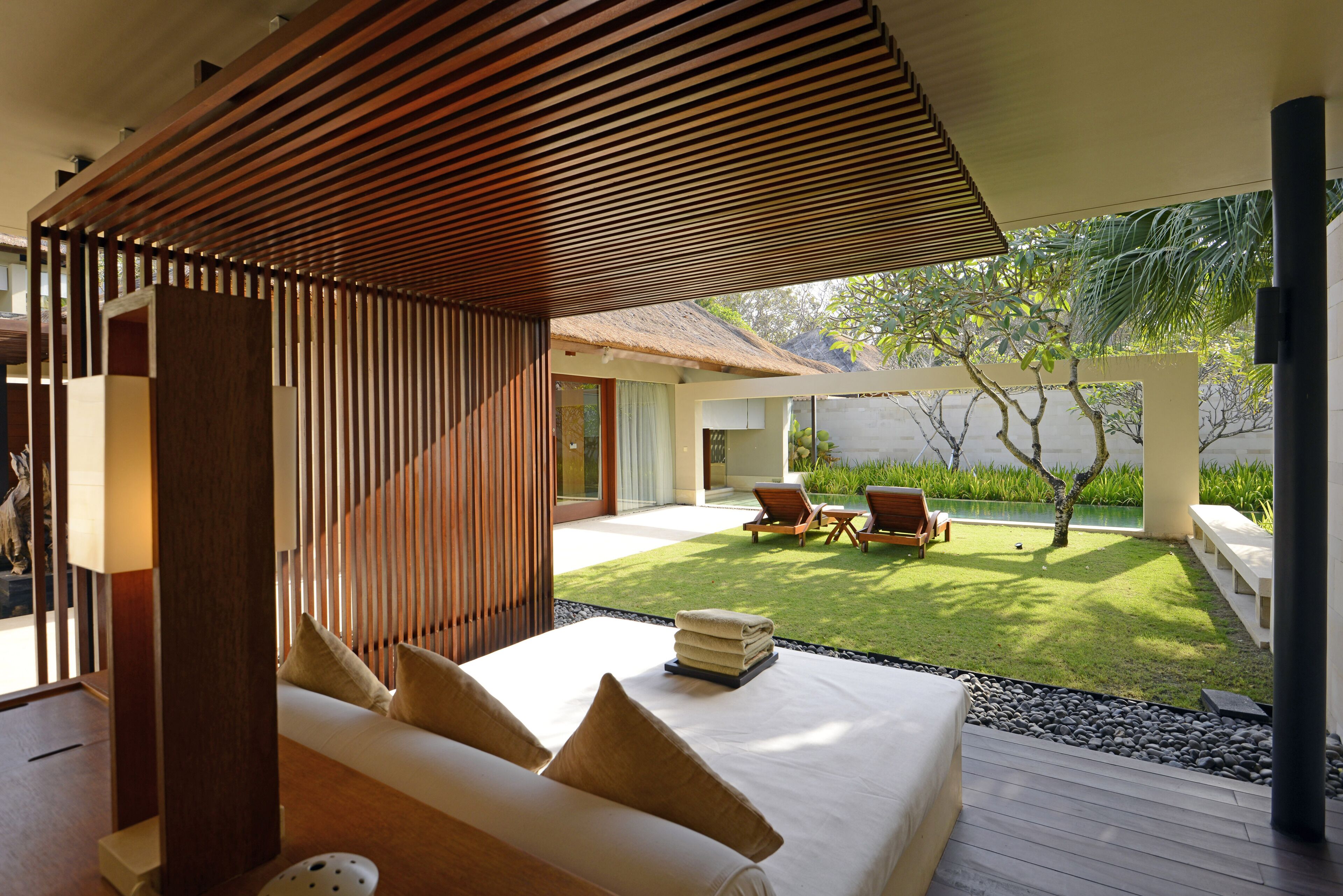 Un dormitorio moderno con una cama grande, detalles de madera y vistas a un jardín cuidado.
