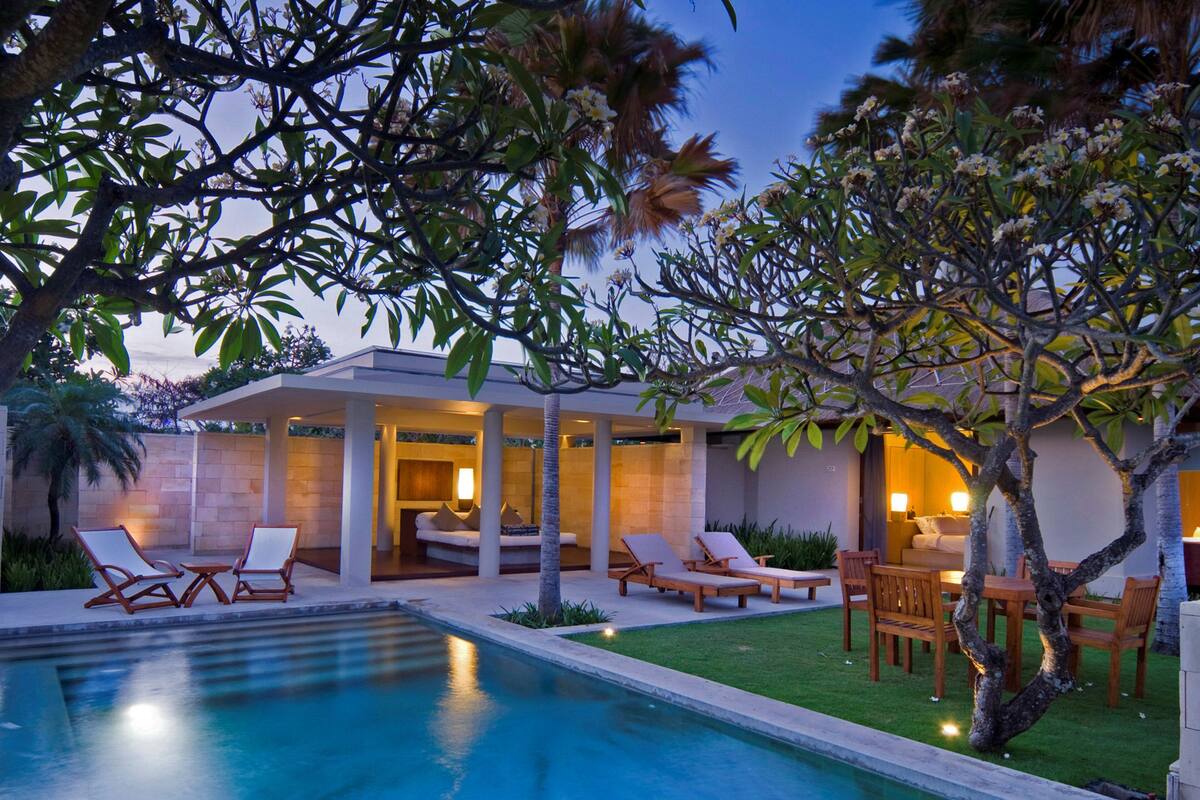 A modern poolside area with lounge chairs and a covered seating area.
