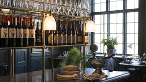 A bar area with wine bottles, glasses, and a potted plant. - Näsby Slott (Taby)