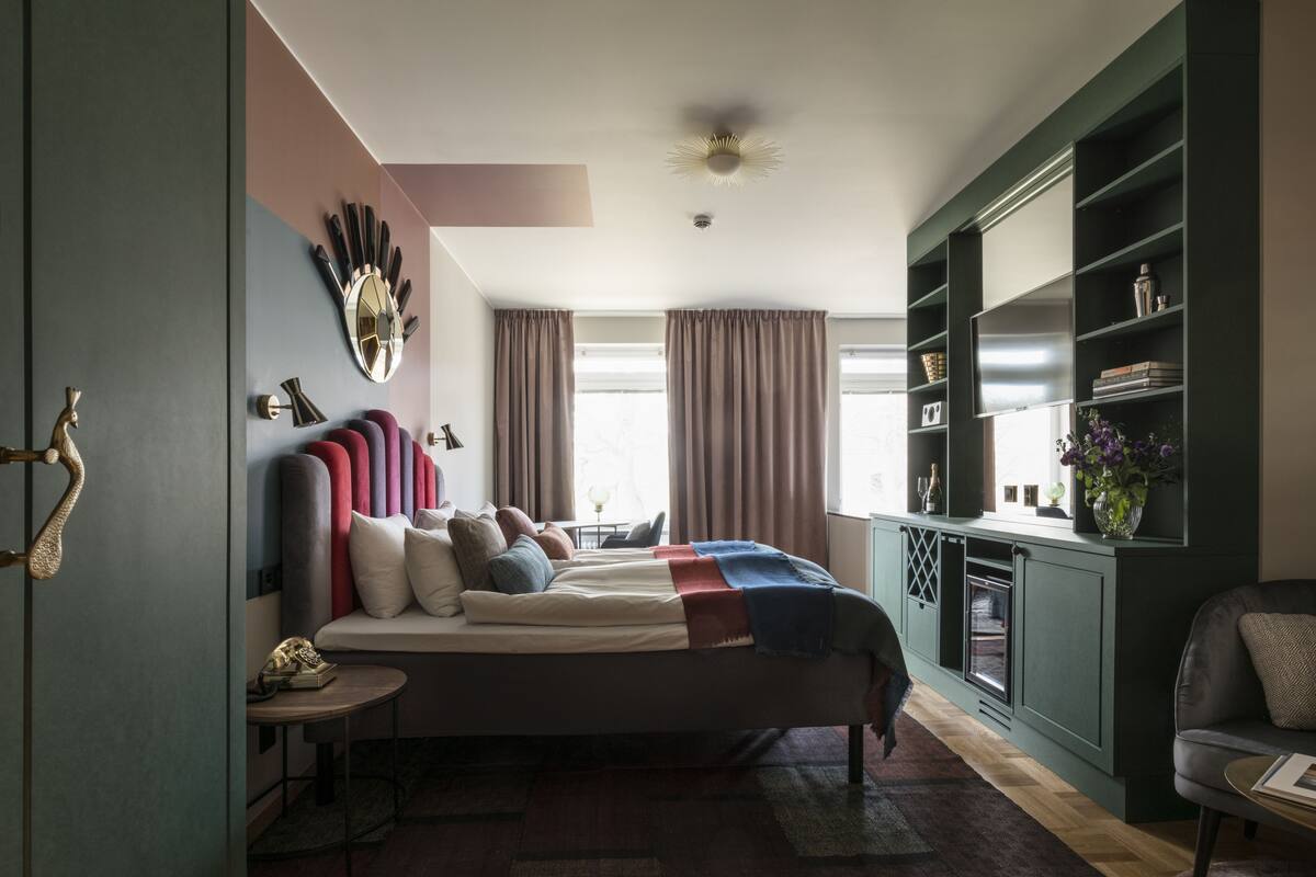 A modern bedroom with a bed, bedside tables, a built-in bookshelf, and a window with curtains.