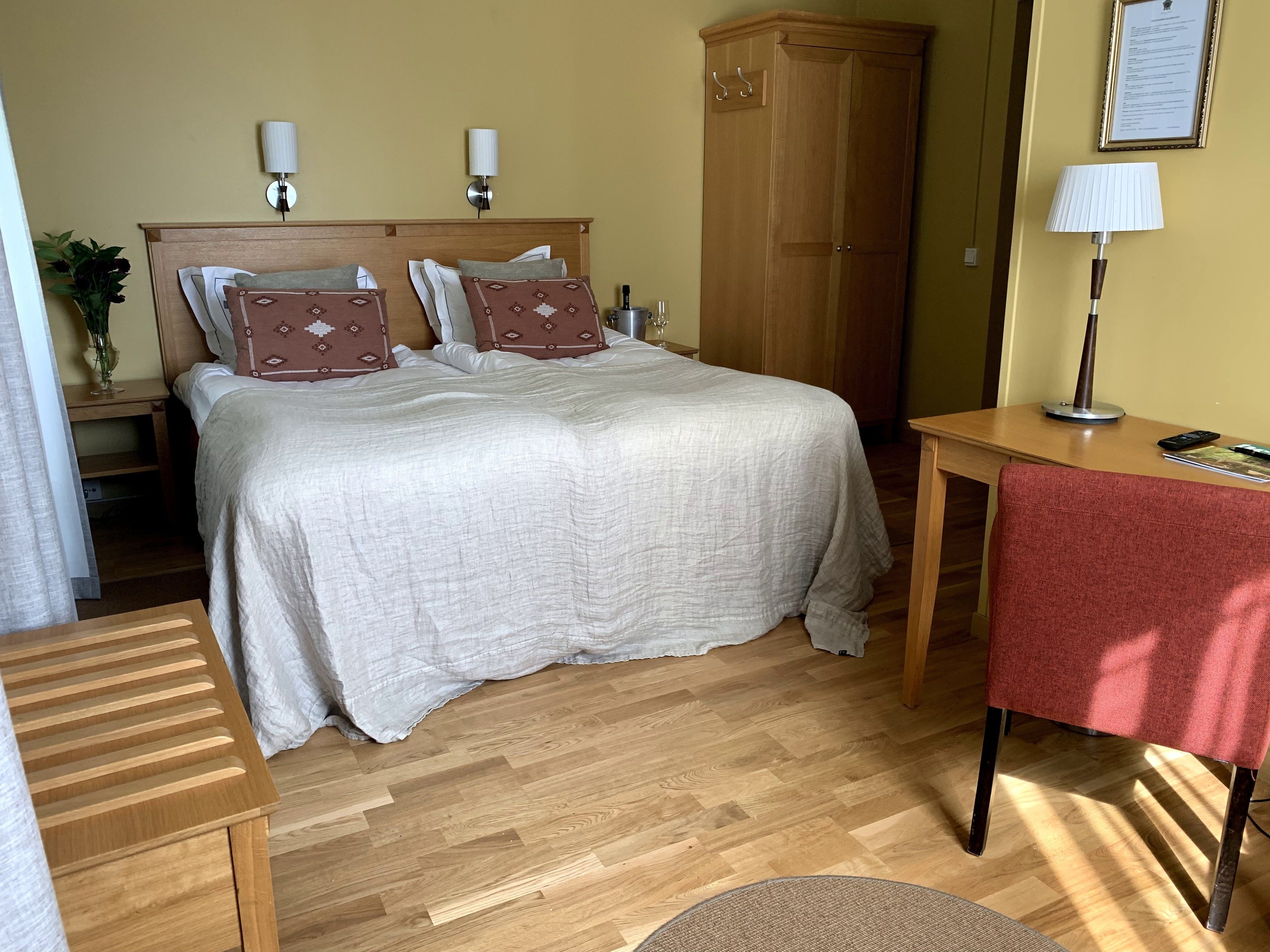 A neatly arranged bedroom with a bed, bedside tables, a wardrobe, and a desk with a chair.