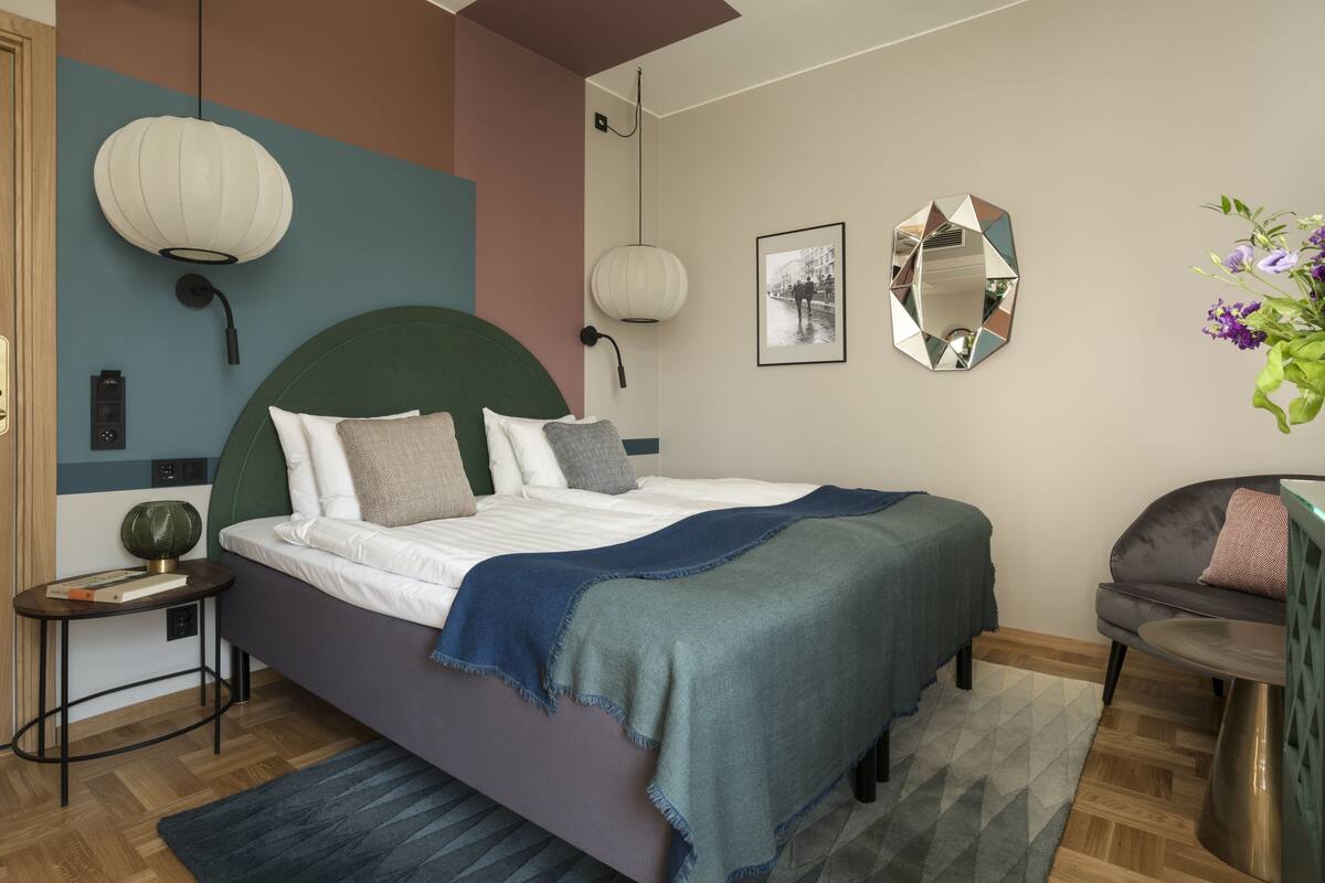 A modern bedroom with a large bed, bedside lamps, and a mirror on the wall.