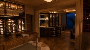 A bar area with a wooden counter, wine bottles, and glasses. There is a seating area with a view of the outdoors. - Villa Nord (Trondheim)