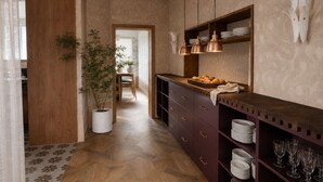 Une cuisine avec des meubles en bois, une plante en pot et un coin repas à l’arrière-plan.