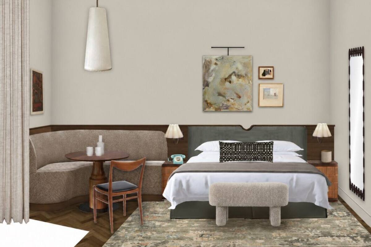 A hotel room with a bed, bedside tables, a chair, a small round table, and a hanging light fixture.