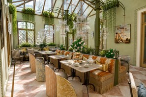 A conservatory with seating, tables, and hanging plants.