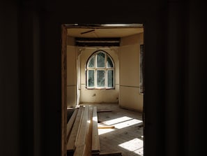 An interior space with a large arched window, wooden flooring, and a door leading outside. - Villa Nord (Trondheim)
