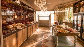 A spacious kitchen with wooden cabinets, a central island, and a variety of food items displayed on shelves and counters.