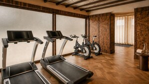 Une salle de sport équipée de tapis de course, de vélos d’appartement et dotée d’un plancher en bois.