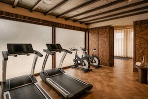 Ein Fitnessstudio mit Laufbändern, Ergometer und Holzboden.