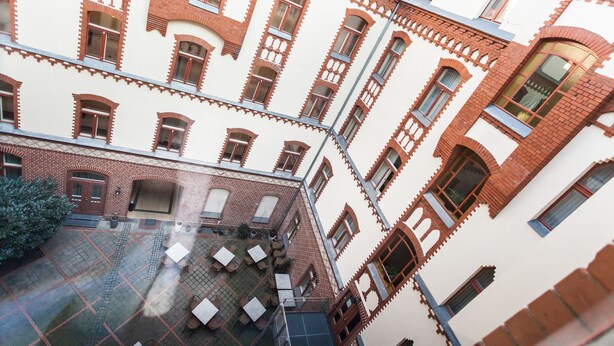 Un immeuble à plusieurs étages doté d’une cour intérieure aménagée avec des espaces de repos en plein air et d’une façade en briques.