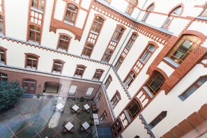 Ein mehrgeschossiges Gebäude mit Innenhof, Außenbestuhlung und einer Ziegel-Fassade.