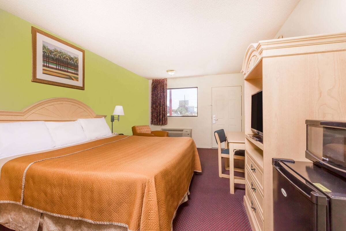 A hotel room with a bed, a desk, a television, and a wardrobe.