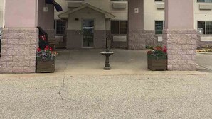 A building with a covered entrance, a central door, and two flower planters. - Osceola Grand Hotel (Evart)