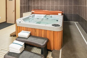 Ein Wellnessbereich mit Whirlpool, Holzliegen und Handtüchern.