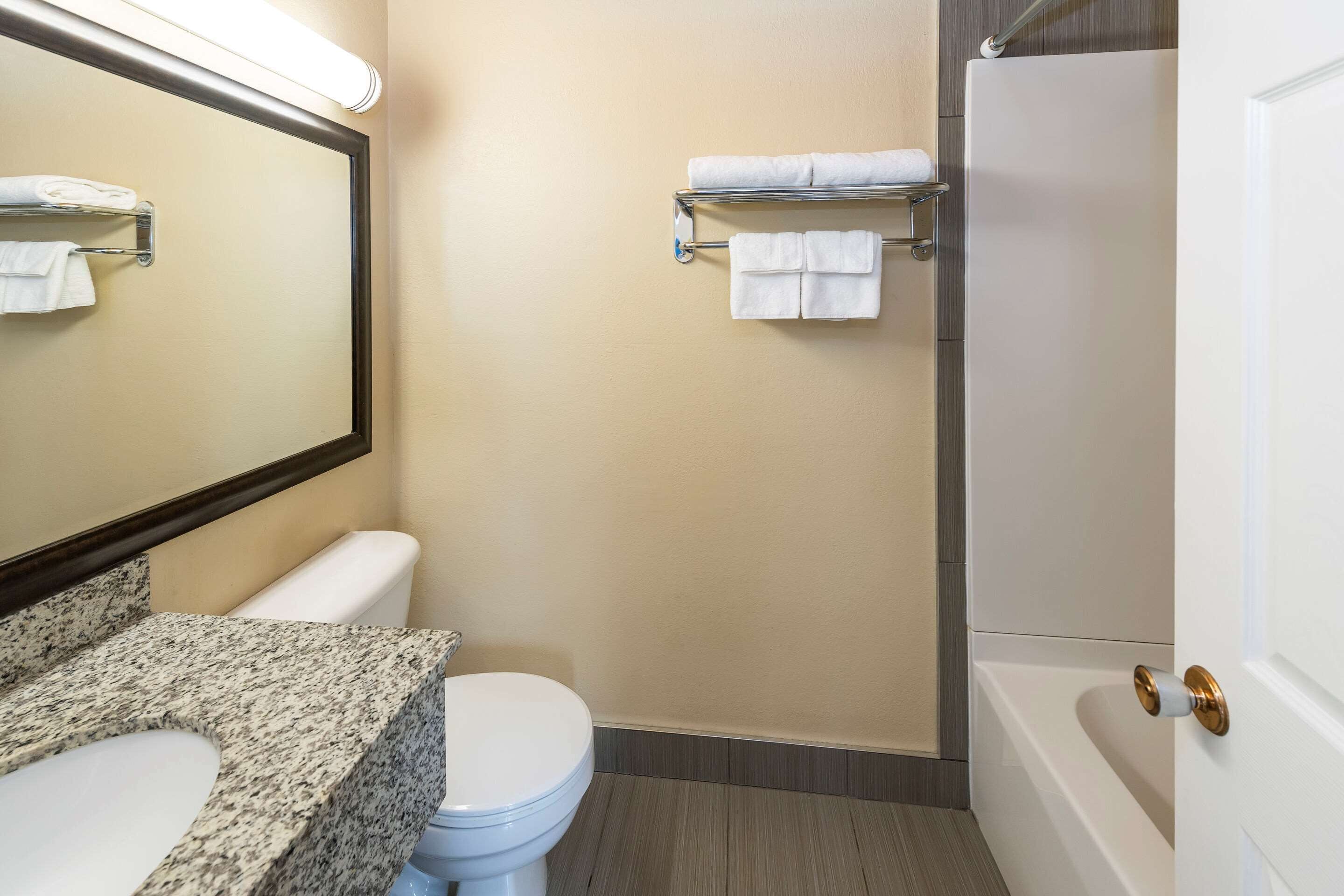A bathroom with a toilet, sink, mirror, towel rack, and bathtub.